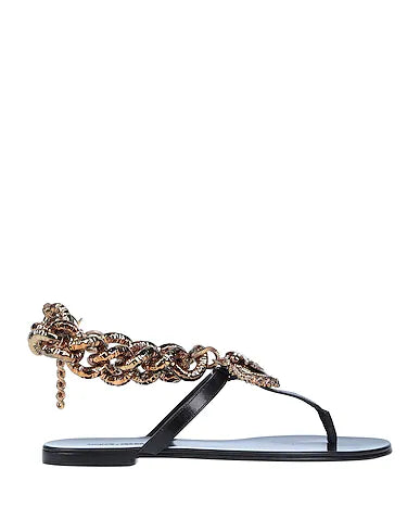 A single black thong sandal featuring a chunky, ornate gold chain strap with a dangling chain detail, shown against a plain white background.