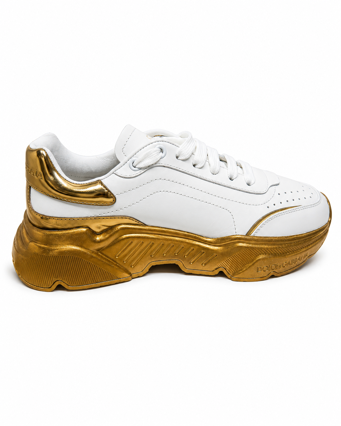 A white leather low-top sneaker with a chunky, sculptural metallic gold sole and gold accents on the heel and toe, shown from a side profile on a white background.