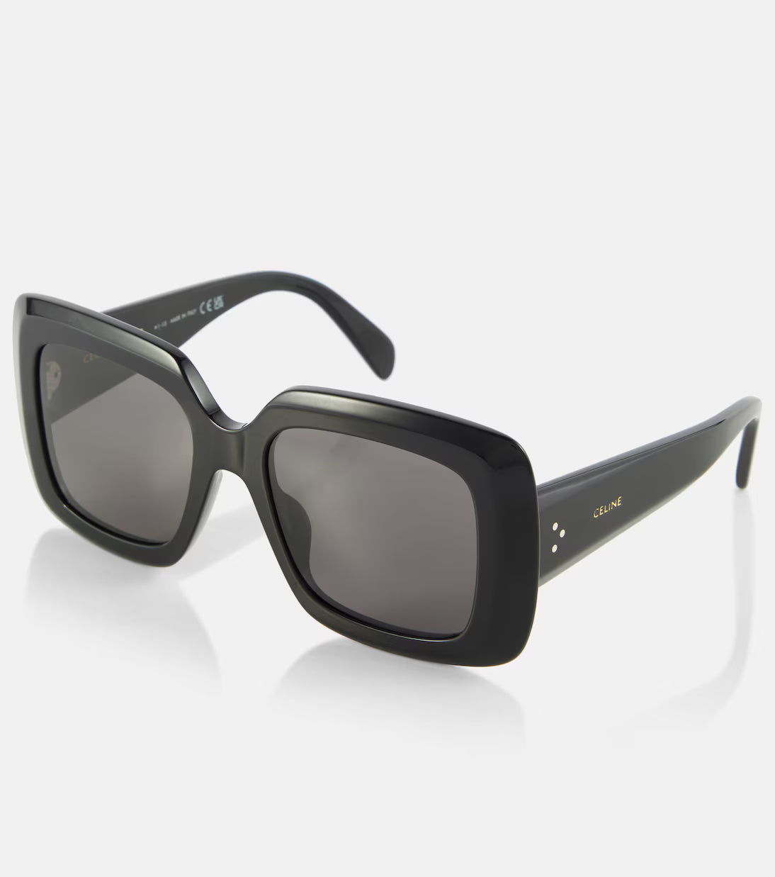 Black square sunglasses with dark lenses and small gold logo details on the temples, shown on a clean light gray background.