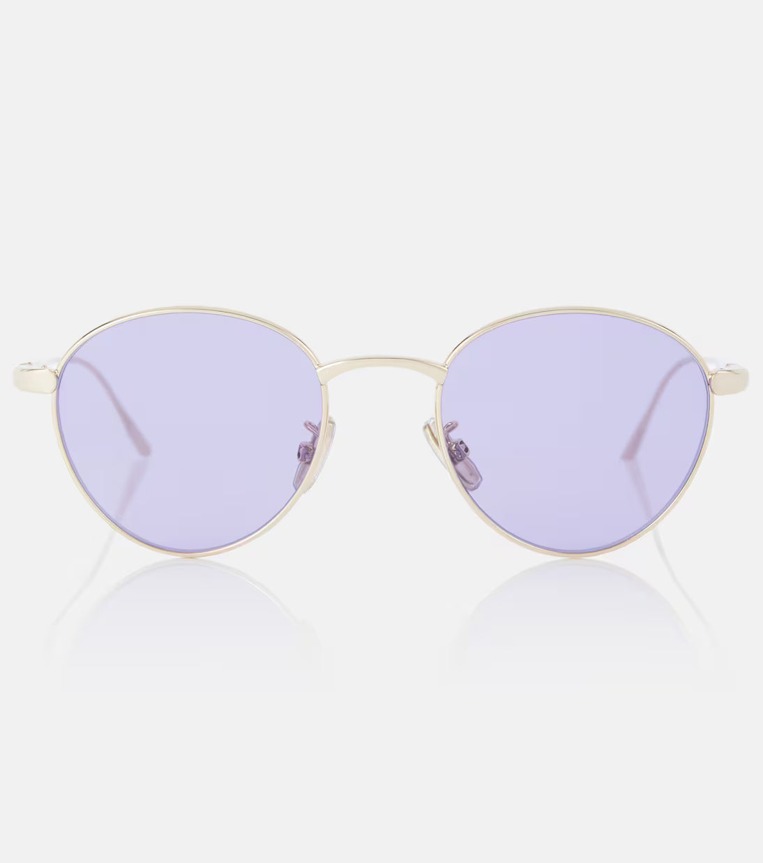 Oval sunglasses with a thin gold metal frame and light purple lenses, shown against a clean white background with a soft reflection below.