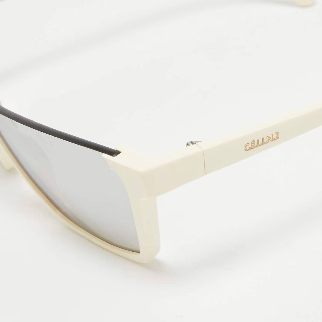 Close-up of a pair of sunglasses with a cream-colored frame and mirrored silver lenses. The brand name 'C'ALLI' is printed in gold on the temple arm.